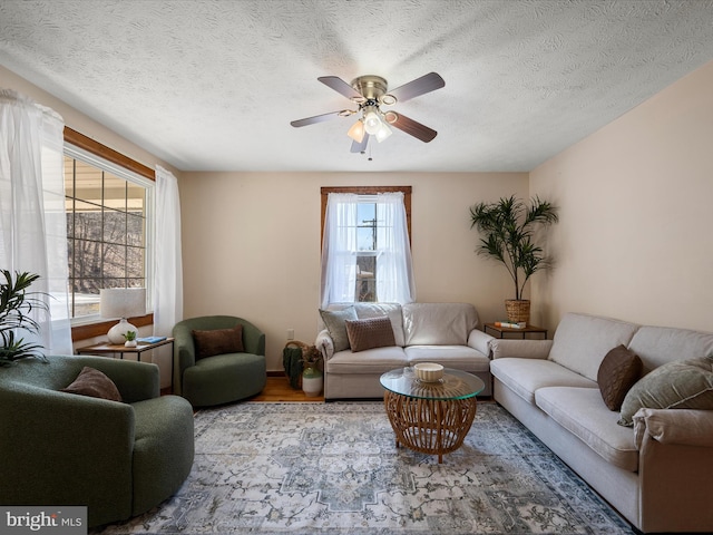 living room with wood finished floors, a textured ceiling, and ceiling fan