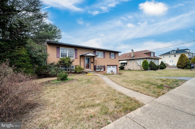 split foyer home featuring brick siding, a garage, and a front yard