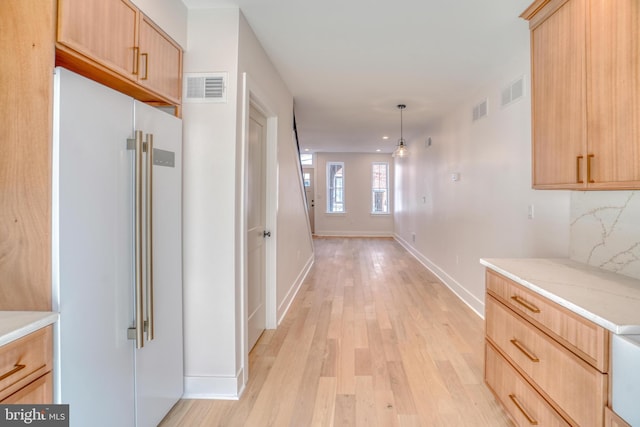 hall with visible vents, baseboards, and light wood-style floors