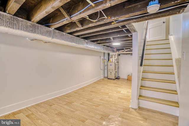 finished basement with heating unit, stairway, baseboards, and wood finished floors