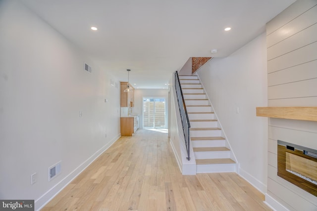 stairs featuring visible vents, recessed lighting, a glass covered fireplace, and hardwood / wood-style flooring