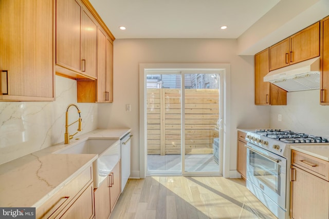 kitchen featuring white appliances, light stone countertops, light wood-style flooring, decorative backsplash, and under cabinet range hood