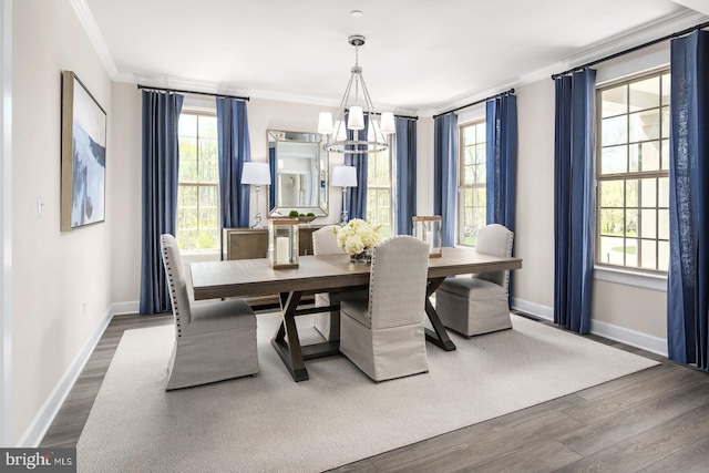 dining area featuring an inviting chandelier, wood finished floors, baseboards, and ornamental molding