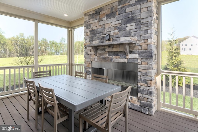 wooden deck featuring outdoor dining area and a stone fireplace