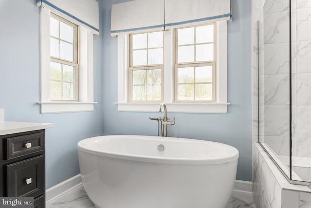 bathroom featuring a soaking tub, plenty of natural light, marble finish floor, and baseboards