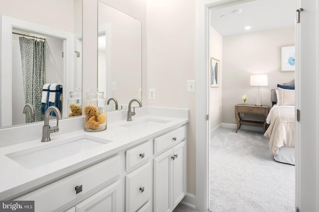 ensuite bathroom with double vanity, ensuite bath, baseboards, and a sink