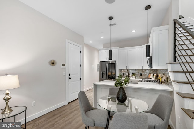 kitchen with visible vents, white cabinetry, stainless steel appliances, a peninsula, and decorative backsplash