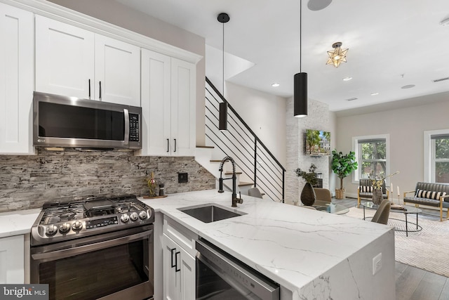 kitchen featuring a sink, white cabinetry, appliances with stainless steel finishes, a peninsula, and decorative backsplash