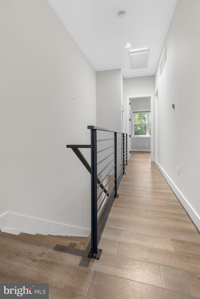 corridor featuring visible vents, an upstairs landing, light wood-style floors, and baseboards