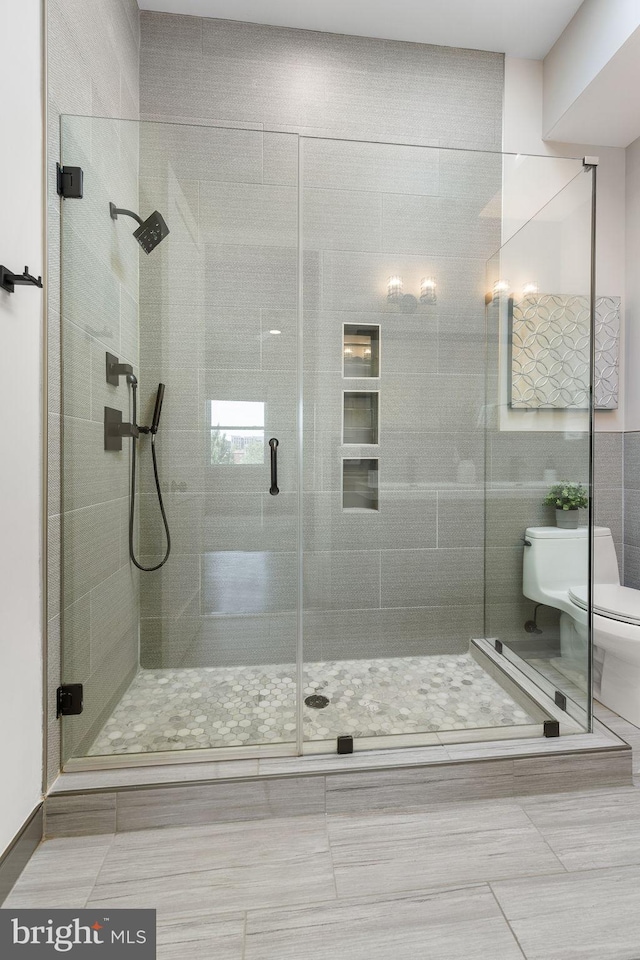 full bathroom featuring a shower stall, toilet, and tile patterned floors