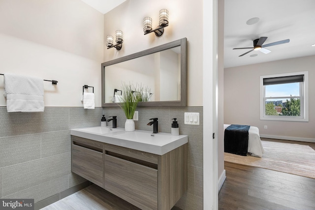 ensuite bathroom featuring ensuite bath, wood finished floors, double vanity, and a sink