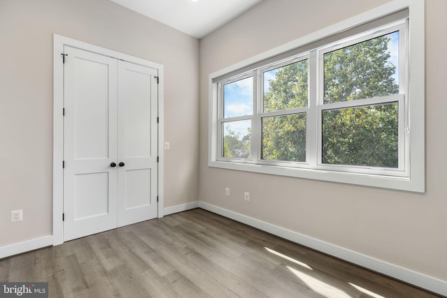 unfurnished bedroom featuring a closet, baseboards, and wood finished floors