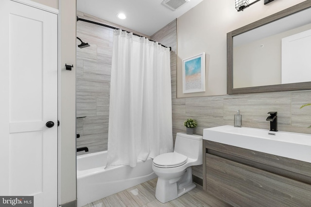 bathroom featuring visible vents, tile walls, toilet, shower / bath combo, and vanity