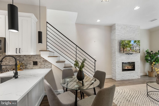 interior space featuring a stone fireplace, dark wood-type flooring, recessed lighting, and visible vents