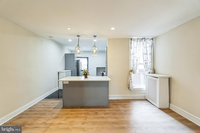 kitchen with baseboards, light wood-style flooring, recessed lighting, freestanding refrigerator, and pendant lighting