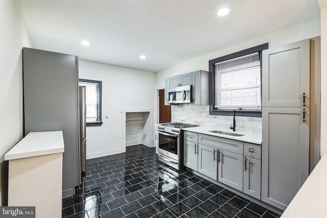 kitchen with tasteful backsplash, gray cabinetry, recessed lighting, stainless steel appliances, and a sink