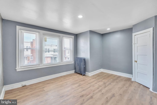 unfurnished room with radiator, recessed lighting, baseboards, and light wood-type flooring