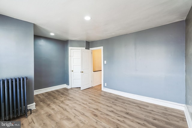 unfurnished room with recessed lighting, baseboards, radiator, and wood finished floors