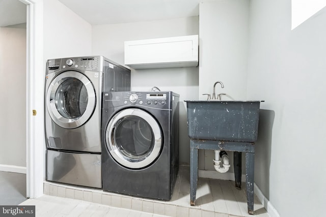 washroom featuring laundry area, independent washer and dryer, baseboards, and a sink