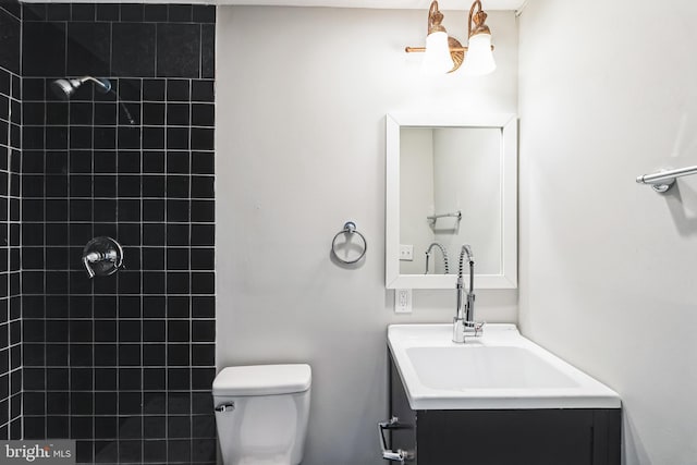 bathroom featuring a tile shower, toilet, and vanity