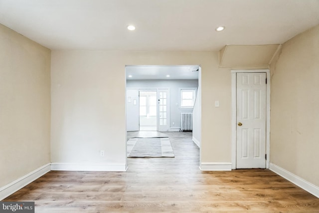 unfurnished room with recessed lighting, baseboards, radiator, and light wood-style flooring