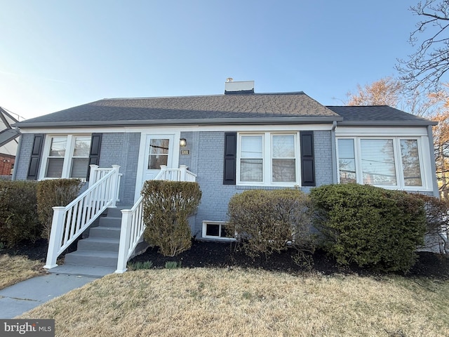 view of front facade with brick siding and a shingled roof