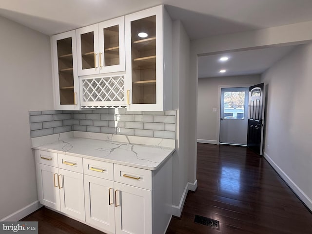 kitchen with light stone countertops, baseboards, dark wood-style flooring, decorative backsplash, and white cabinets