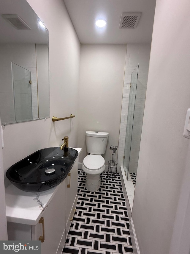 bathroom with vanity, a shower stall, toilet, and visible vents