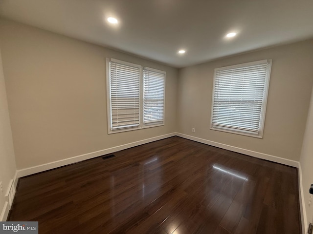 unfurnished room with baseboards, visible vents, recessed lighting, dark wood-type flooring, and a wealth of natural light