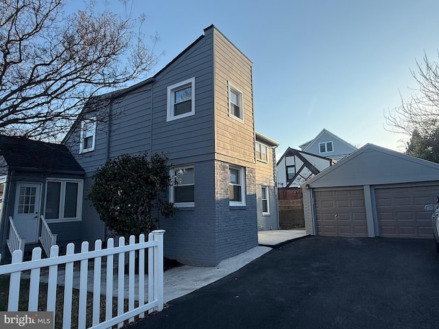 view of home's exterior with an outbuilding, a garage, fence private yard, and brick siding