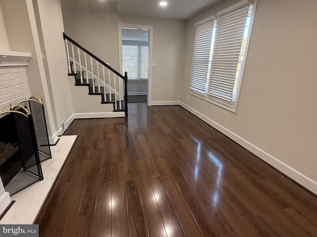 unfurnished living room featuring stairway, baseboards, and hardwood / wood-style flooring