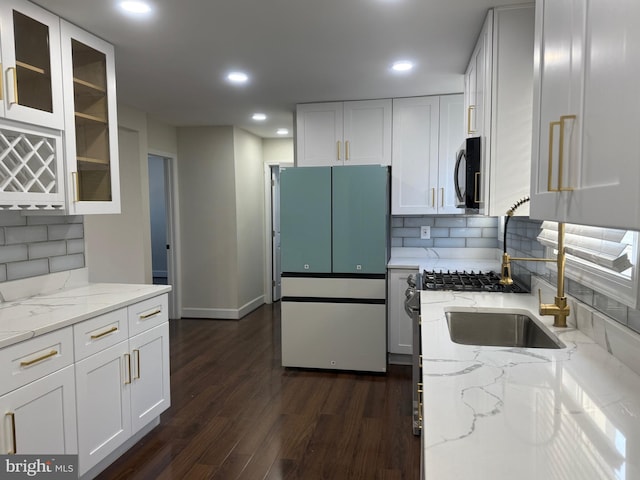 kitchen featuring dark wood-type flooring, black microwave, light stone countertops, freestanding refrigerator, and white cabinetry