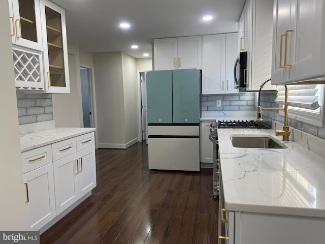 kitchen featuring glass insert cabinets, light stone counters, freestanding refrigerator, white cabinets, and dark wood-style flooring