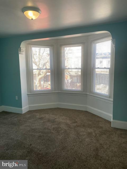 carpeted spare room with baseboards and arched walkways