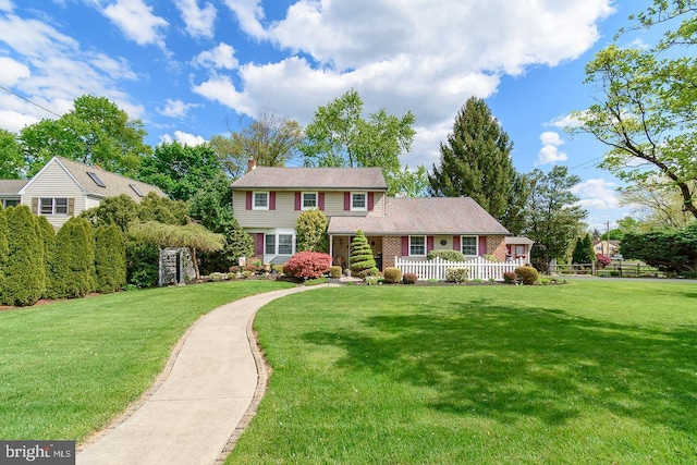 view of front of home with brick siding, a front lawn, a chimney, and fence