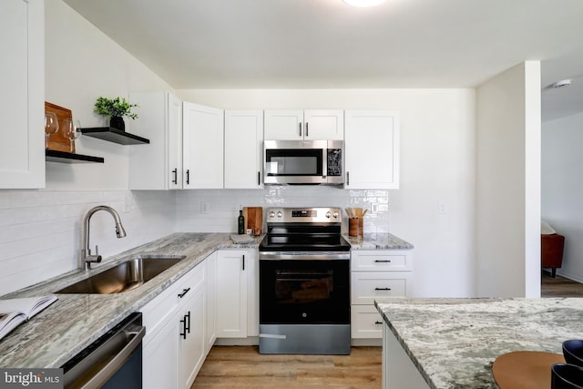 kitchen featuring a sink, light stone countertops, appliances with stainless steel finishes, white cabinetry, and open shelves