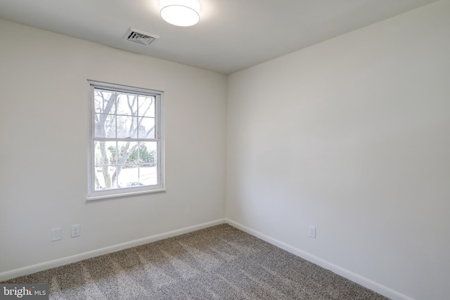 spare room with carpet, visible vents, and baseboards