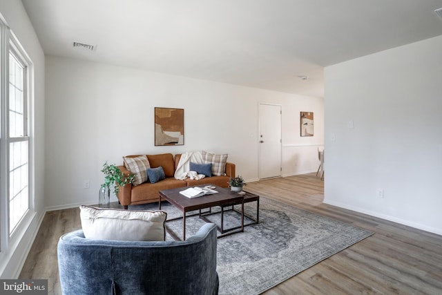 living area with wood finished floors, visible vents, and baseboards