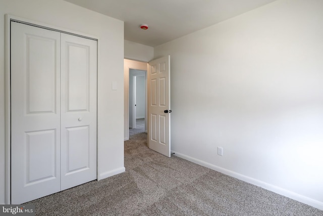 unfurnished bedroom with a closet, baseboards, and carpet floors