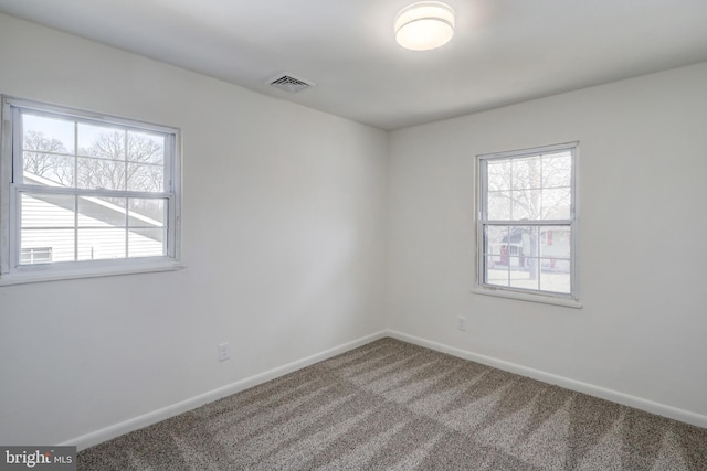 spare room featuring baseboards, carpet, visible vents, and a healthy amount of sunlight