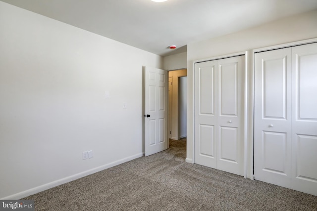 unfurnished bedroom featuring carpet flooring, baseboards, and two closets