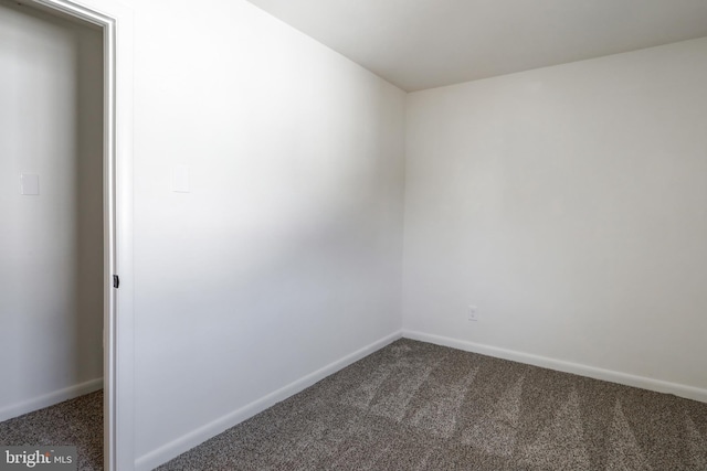 empty room with baseboards and dark carpet