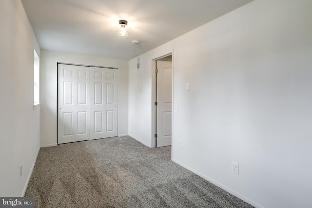 unfurnished bedroom with carpet, baseboards, and a closet