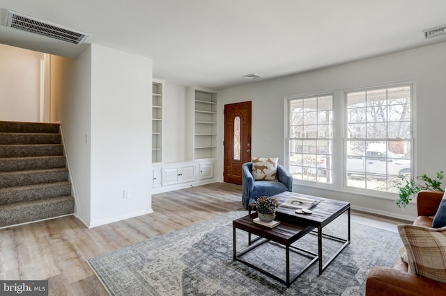 living room with visible vents, wood finished floors, and stairway