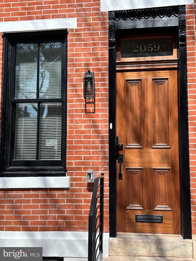 doorway to property featuring brick siding