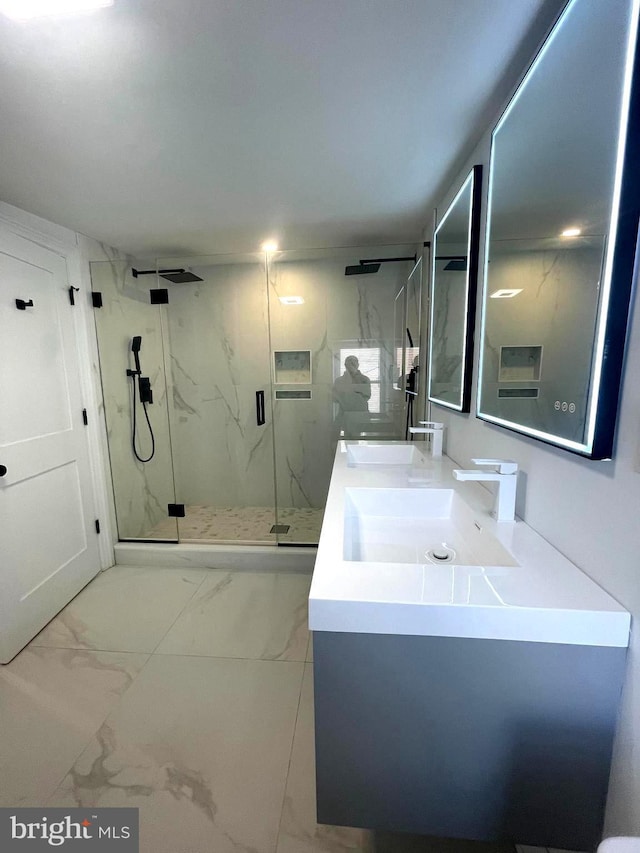 full bath with a sink, a marble finish shower, marble finish floor, and double vanity