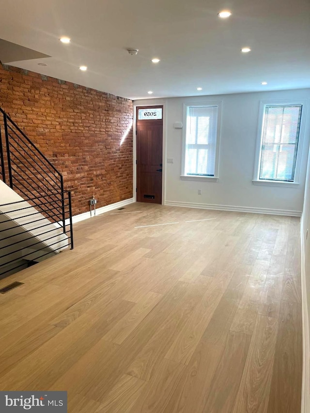 foyer featuring visible vents, brick wall, baseboards, recessed lighting, and light wood-style flooring