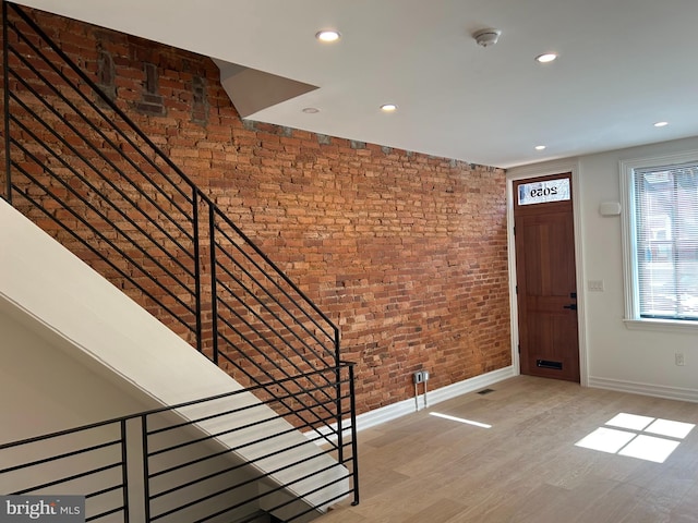 entryway with light wood finished floors, recessed lighting, brick wall, and baseboards