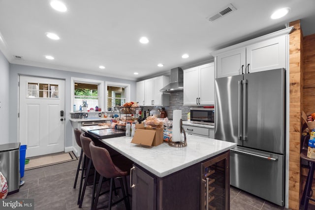 444 Grindall St, Baltimore, MD 21230 - kitchen with appliances with stainless steel finishes, wall chimney exhaust hood, beverage cooler, dark tile patterned flooring, and white cabinetry