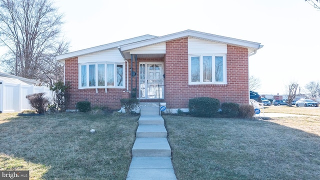 bungalow-style home with a front lawn, fence, and brick siding